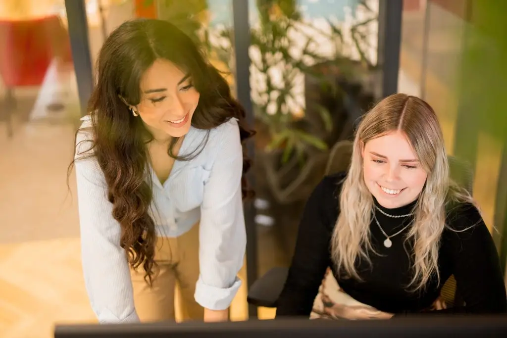 Onze medewerkers Niusha en Lieke overleggen achter een bureau